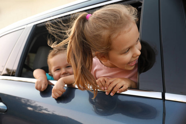屋外で家族の車から見て幸せな小さな子供たち - 写真・画像