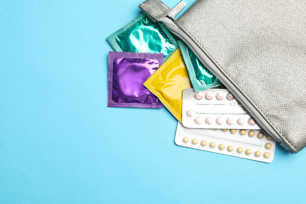 Flat lay composition with birth control pills and condoms on light blue background. Safe sex concept - Foto, imagen