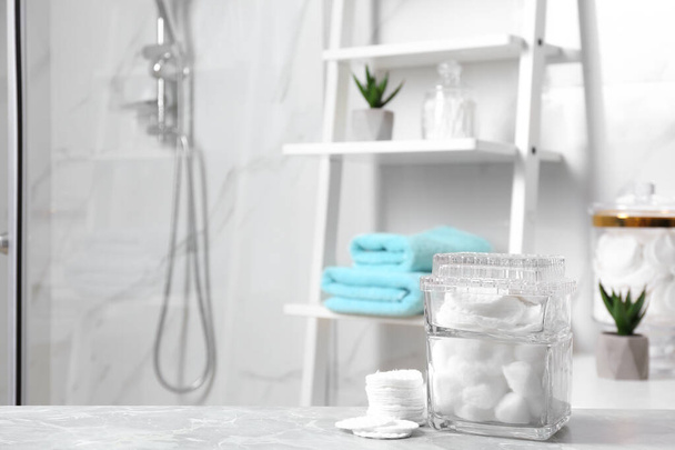 Cotton pads and balls on light grey marble table in bathroom - Foto, Bild