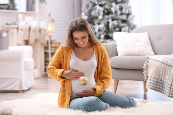 Young pregnant woman with Christmas decoration at home - 写真・画像