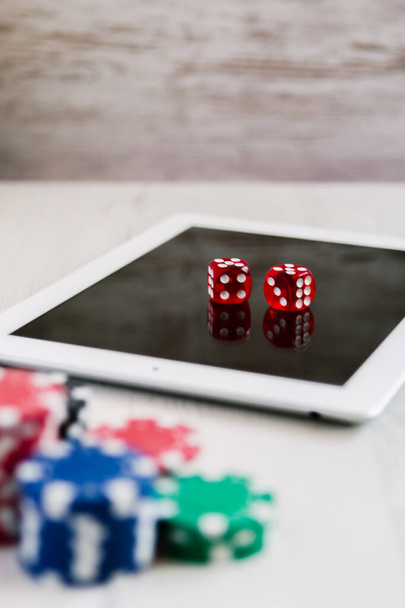 Poker żetony i czerwone kości na tablecie z miejscem na tekst na tle. Koncepcja gry i zakładów online. - Zdjęcie, obraz