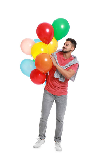 Young man holding bunch of colorful balloons on white background - Photo, image