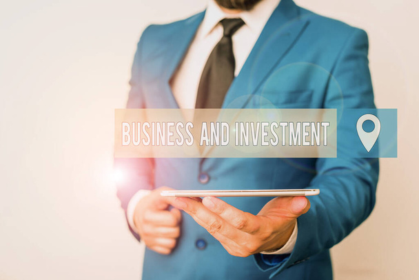 Γράφοντας σημείωμα που δείχνει Επιχειρήσεις και Επενδύσεις. Επαγγελματική φωτογραφία προβάλλοντας βάζοντας τα χρήματά σας στο πεδίο για την αύξηση τους Επιχειρηματίας σε μπλε σουίτα με γραβάτα κατέχει lap top στα χέρια. - Φωτογραφία, εικόνα