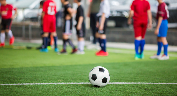 Ποδόσφαιρο μπάλα σε πράσινο τεχνητό χλοοτάπητα με θολή ομάδα ποδοσφαίρου tra - Φωτογραφία, εικόνα