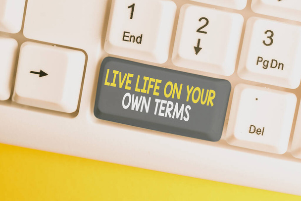 Conceptual hand writing showing Live Life On Your Own Terms. Business photo showcasing Give yourself guidelines for a good living White pc keyboard with note paper above the white background. - Photo, Image