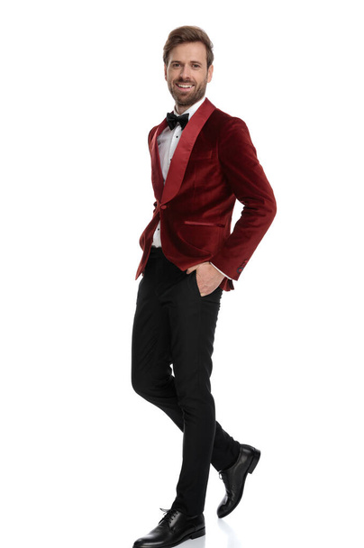smiling groom wearing red velvet tuxedo and walking - Foto, immagini