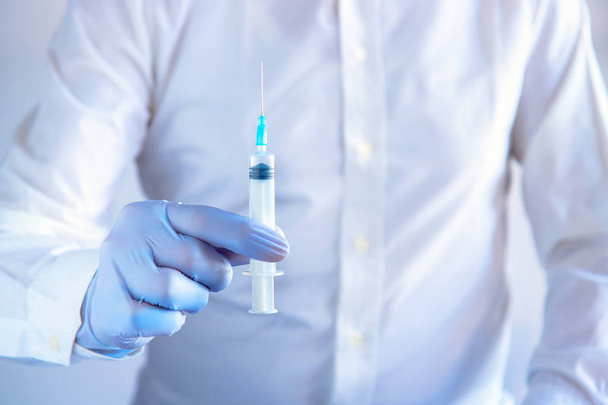 injection médicale à la main, vue de face du médecin portant un gant bleu tenant une seringue
 - Photo, image
