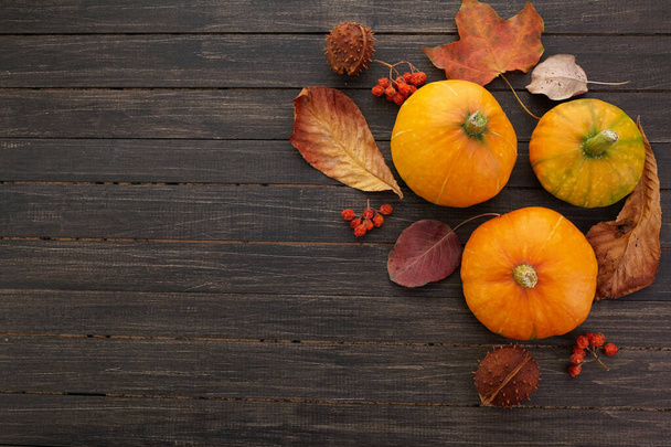 Pumpkins and fallen leaves on wooden background. Halloween, Thanksgiving day or seasonal background - 写真・画像