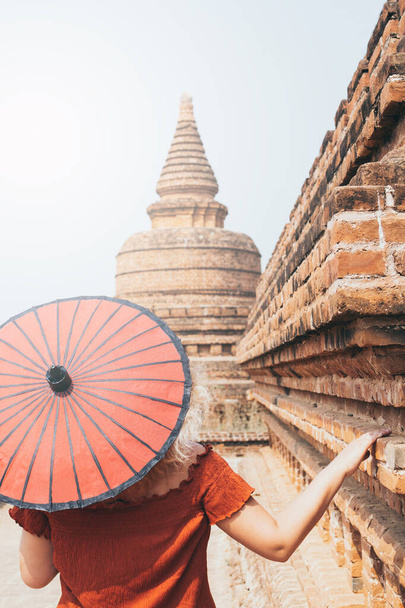 Vrouw met rode paraplu met uitzicht op pagode en de tempel van het oude Bagan in Myanmar - Foto, afbeelding