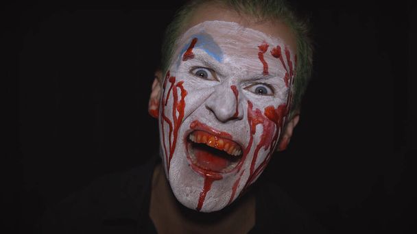Bohóc Halloween férfi portré. Ijesztő, gonosz bohócok véres arca. Fehér arc smink - Fotó, kép