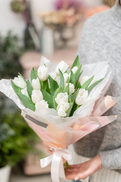 女性の手に白いチューリップの花の美しい花束。花屋さんのお花屋さんの仕事。可愛い子ね - 写真・画像
