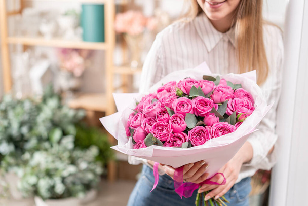 Lots of buds Roses of pink fuchsia color. Bouquet in woman hand. the work of the florist at a flower shop Flower shop concept - Photo, Image