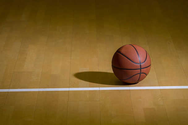 μια μπάλα του μπάσκετ στο ξύλινο πάτωμα ως φόντο - Φωτογραφία, εικόνα