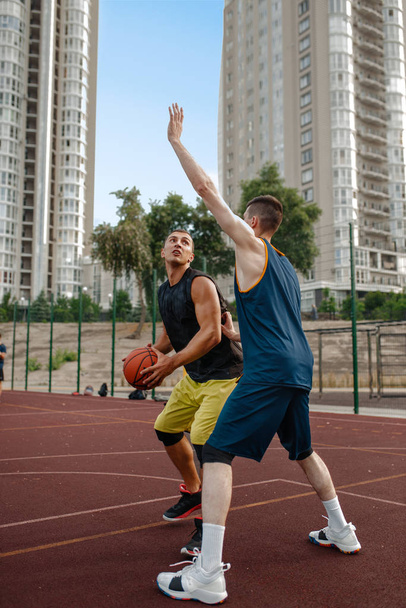 Zwei Basketballer üben auf dem Außenplatz Taktik. Männer in Sportbekleidung spielen beim Streetball-Training das Spiel - Foto, Bild