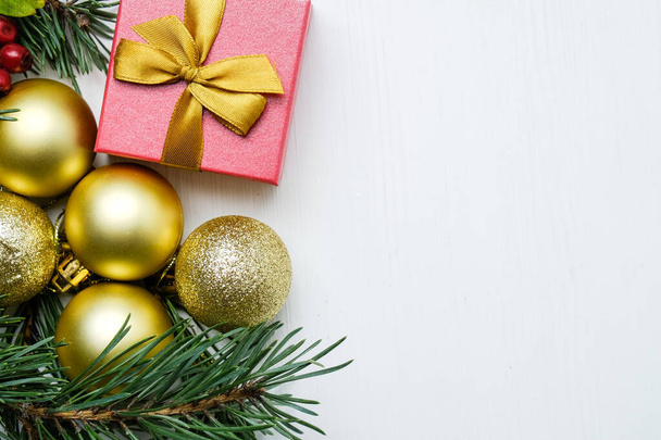 Złote noworoczne kulki na gałęziach sosny z prezentem z przestrzenią do kopiowania. - Zdjęcie, obraz