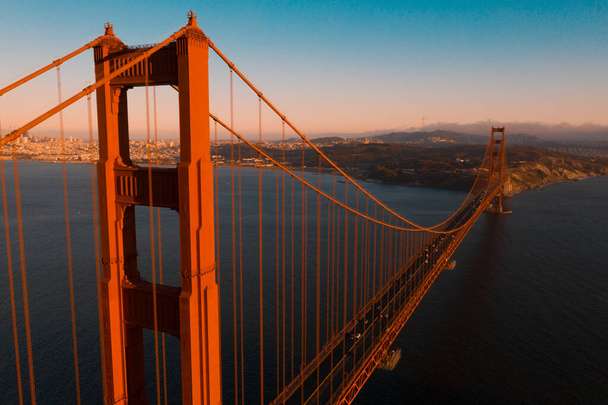 Vista aérea al atardecer del Puente Golden Gate sobre el Área Recreativa Nacional Golden Gate, en San Francisco, California
. - Foto, Imagen