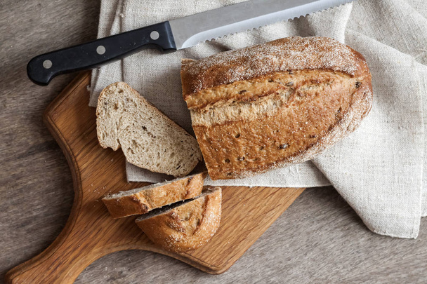 Mutfak masasında ahşap tahta üzerinde dilimleri ile tüm buğday ekmeği Loaf - Fotoğraf, Görsel
