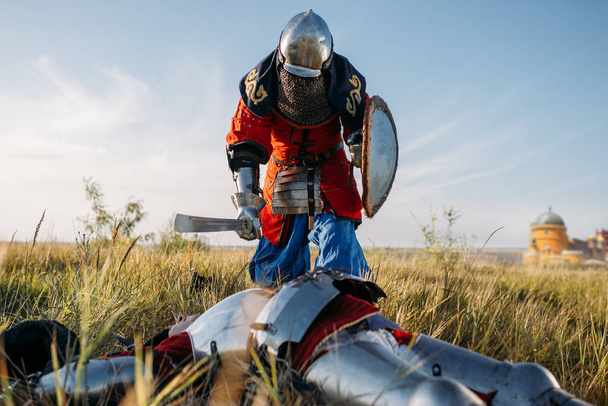 Medieval knight in armor and helmets put his sword to his opponent's throat. Armored ancient warrior in armour posing in the field - Photo, Image