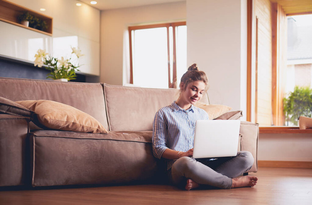 Happy woman with laptop on living room floor - Valokuva, kuva