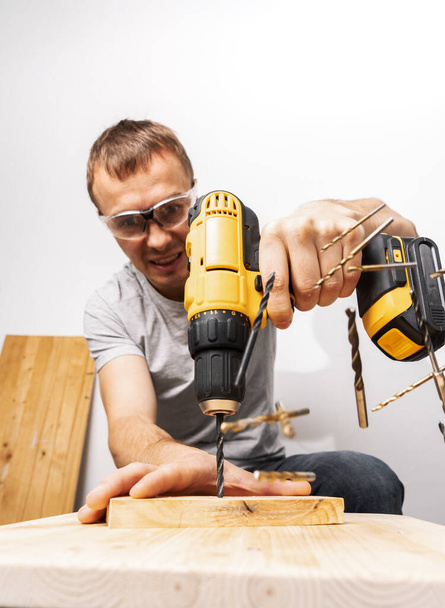 A man drills with a yellow screwdriver. - Фото, зображення