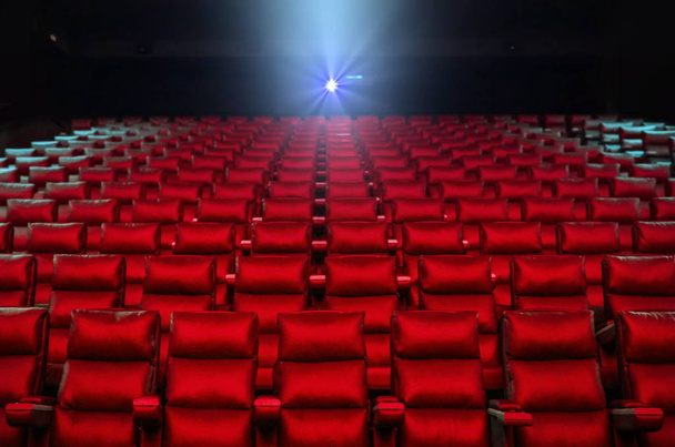 Asientos de cine con proyector luminoso en el fondo
 - Foto, Imagen