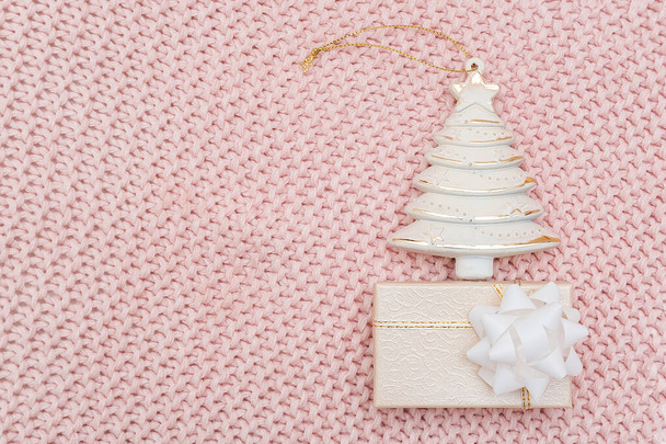 Decorative beige christmas tree and gift box on pink knitted background. New Year or Christmas concept. Top view Flat lay Template for design, greeting card, invitation - Photo, image