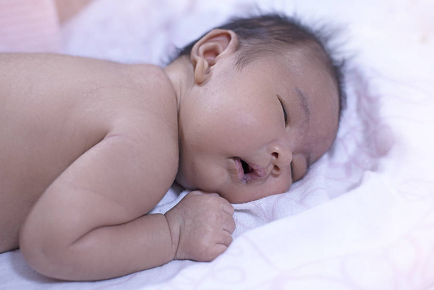 Il neonato che dorme, gli occhi chiusi e ha aperto il labbro piccolo, lo sfondo sfocato di disegno leggero - Foto, immagini