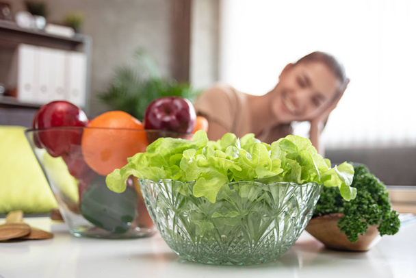 En el enfoque selectivo de verduras verdes en gran golpe, frente a la hermosa mujer borrosa, prepararse para hacer ensalada, comida saludable, buena para la vida
 - Foto, imagen