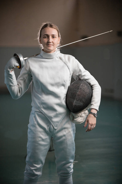 Eine junge Fechterin steht mit einem Schwert auf dem Rücken in der Schulsporthalle - Foto, Bild