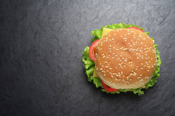 klassischer Cheeseburger auf schwarzem Schiefergrund - Foto, Bild