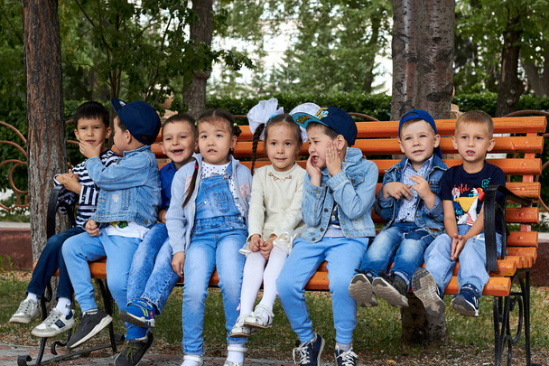 Skupina dětí sedících na lavičce v parku. - Fotografie, Obrázek