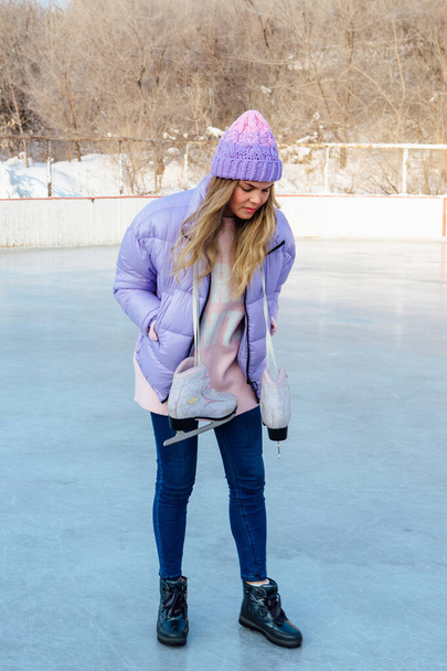 Lovely young woman with ice skates hanging on neck on the ice rink. - Foto, Imagen