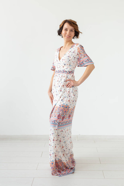 服のデザイナーと人々のコンセプト - 白い背景の上に床の長さのドレスの女性 - 写真・画像