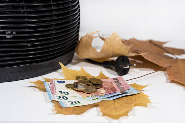 Money for heating bills with black heater on white background. Autumn season. - Photo, Image