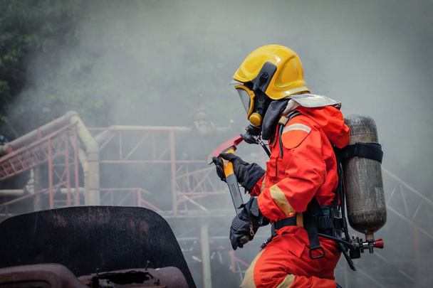 Bombeiro vestindo suíte de segurança e caminhando para área de dano de fogo com fumaça para combate a incêndio, conceito de segurança contra incêndio
 - Foto, Imagem