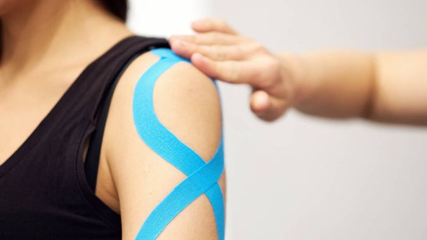 Yaralı kadın kolunda mavi bant ile kineziyoloji bandı tedavisi. Spor yaralanması kinesio tedavisi - Fotoğraf, Görsel