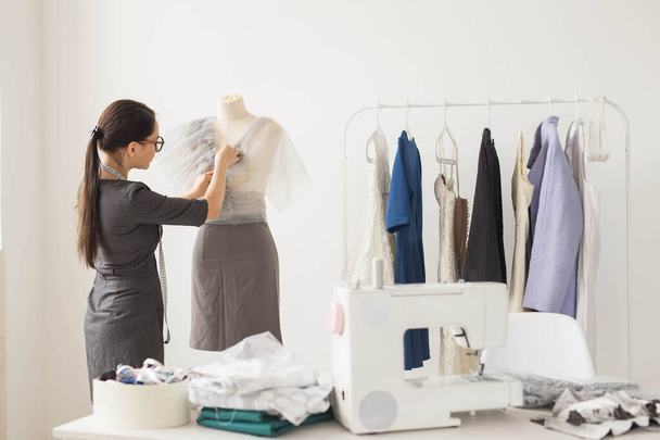 Dressmaker, technologies, fashion designer and tailor concept - young female fashion designer working in her showroom - 写真・画像