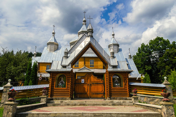 Verchovjna, Oekraïne. Prachtige houten orthodoxe kerk op een achtergrond van de zomer bewolkte hemel - Foto, afbeelding