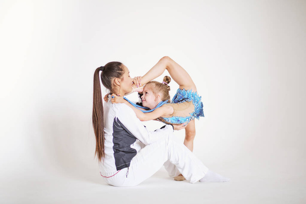 Asian teacher on white background teaches some steps to his young student who wants to learn gymnastics. Concept of: ambition, education, teaching and love for the dance - Photo, Image