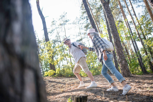 Husband holding hand of wife while hiking in forest together - Valokuva, kuva