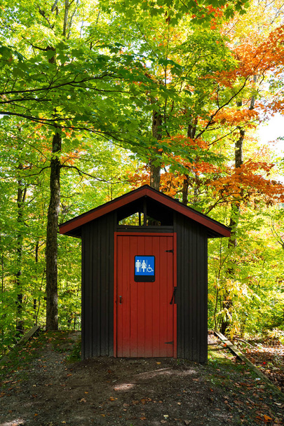 Magnífico baño público rojo y marrón en medio del bosque, Gatineau Park, Quebec, Canadá
. - Foto, imagen