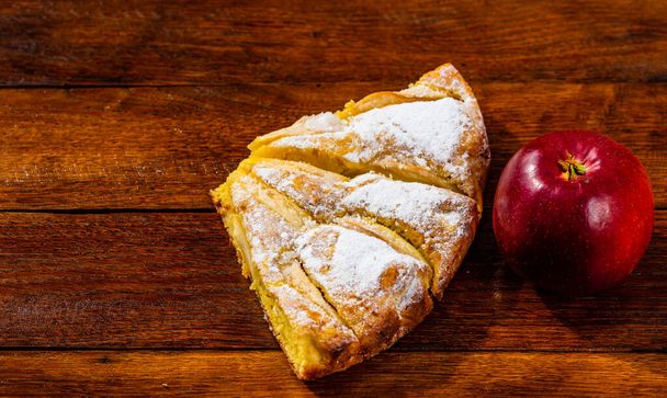 Viipaleita vastaleivottua omenapiirakkaa sokerijauheella ja punaisella applilla
 - Valokuva, kuva
