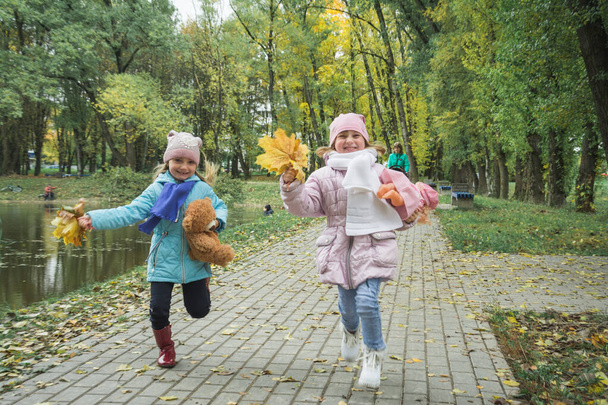 Two sisters five years old run in the autumn park - Photo, image