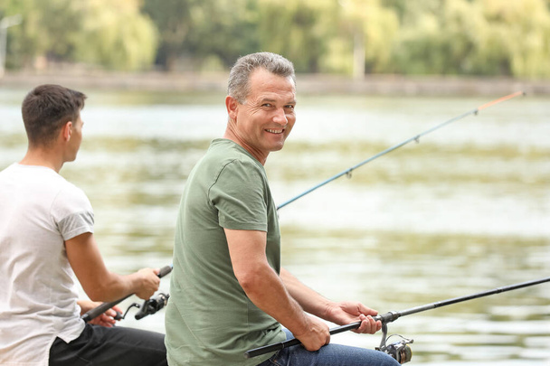 Joven y su padre pescando en el río
 - Foto, imagen