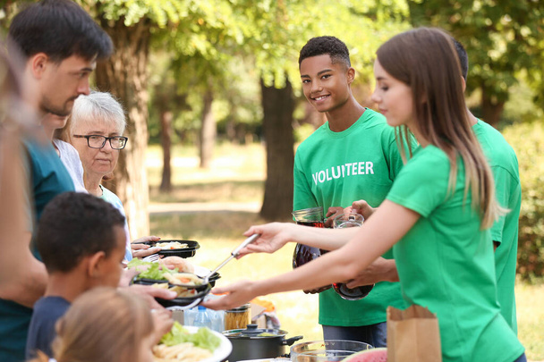 Jóvenes voluntarios dando comida a los pobres al aire libre
 - Foto, imagen