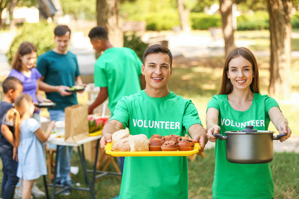 Young volunteers with food for poor people outdoors - 写真・画像