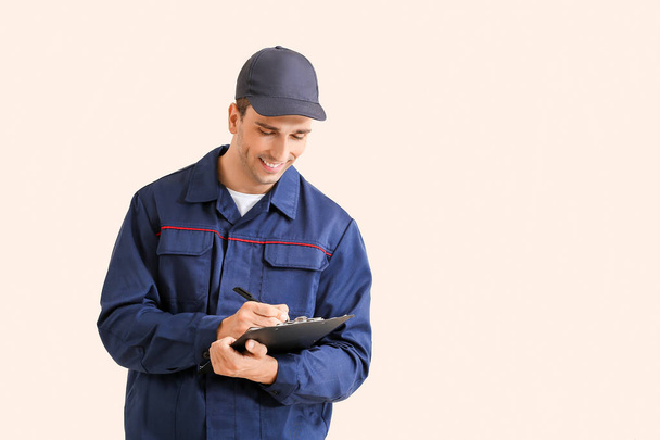 Male car mechanic with clipboard on color background - 写真・画像