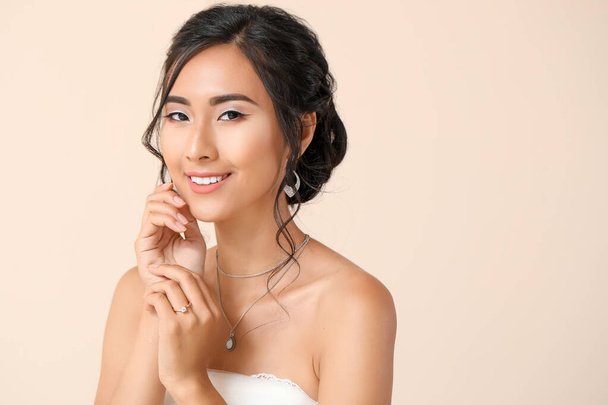 Beautiful young Asian bride on light color background - Fotó, kép
