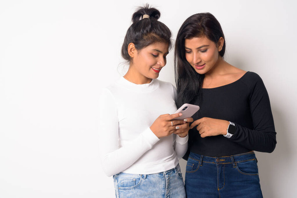 Two happy young beautiful Persian women using phone together - Foto, Imagem