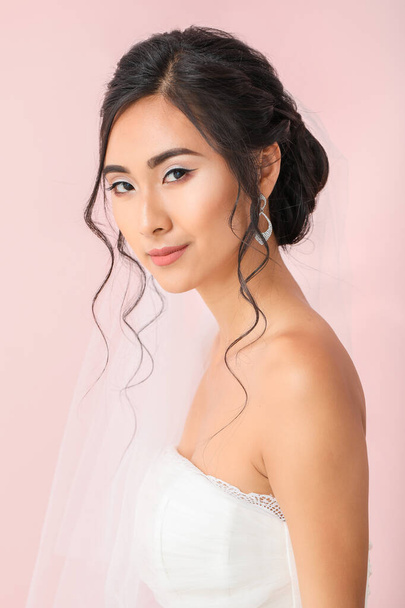 Beautiful young Asian bride on color background - Фото, зображення